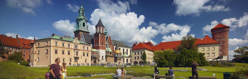 People sitting on the benches, in the background a view of the church and the castle.